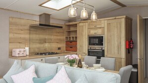 A modern kitchen with wooden cabinets, a gas stove, an oven, and a skylight. - Maple Lodge (Newton Abbot)