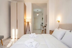 A hotel room with a bed, a desk, a chair, and a lamp.