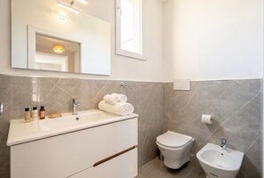 A modern bathroom with a white vanity, a toilet, and a bidet.