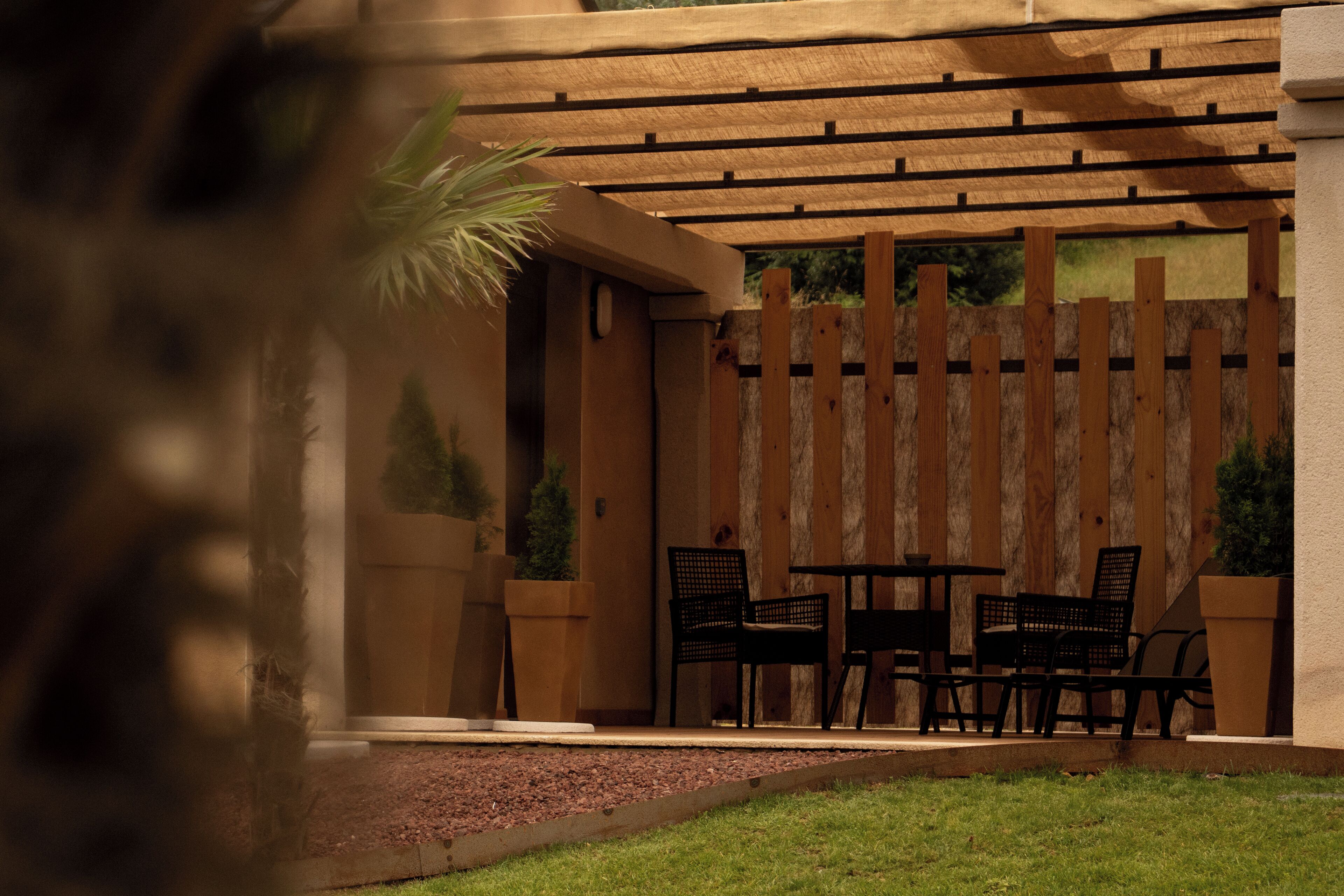 A patio area with a pergola, wooden fence, and outdoor seating.