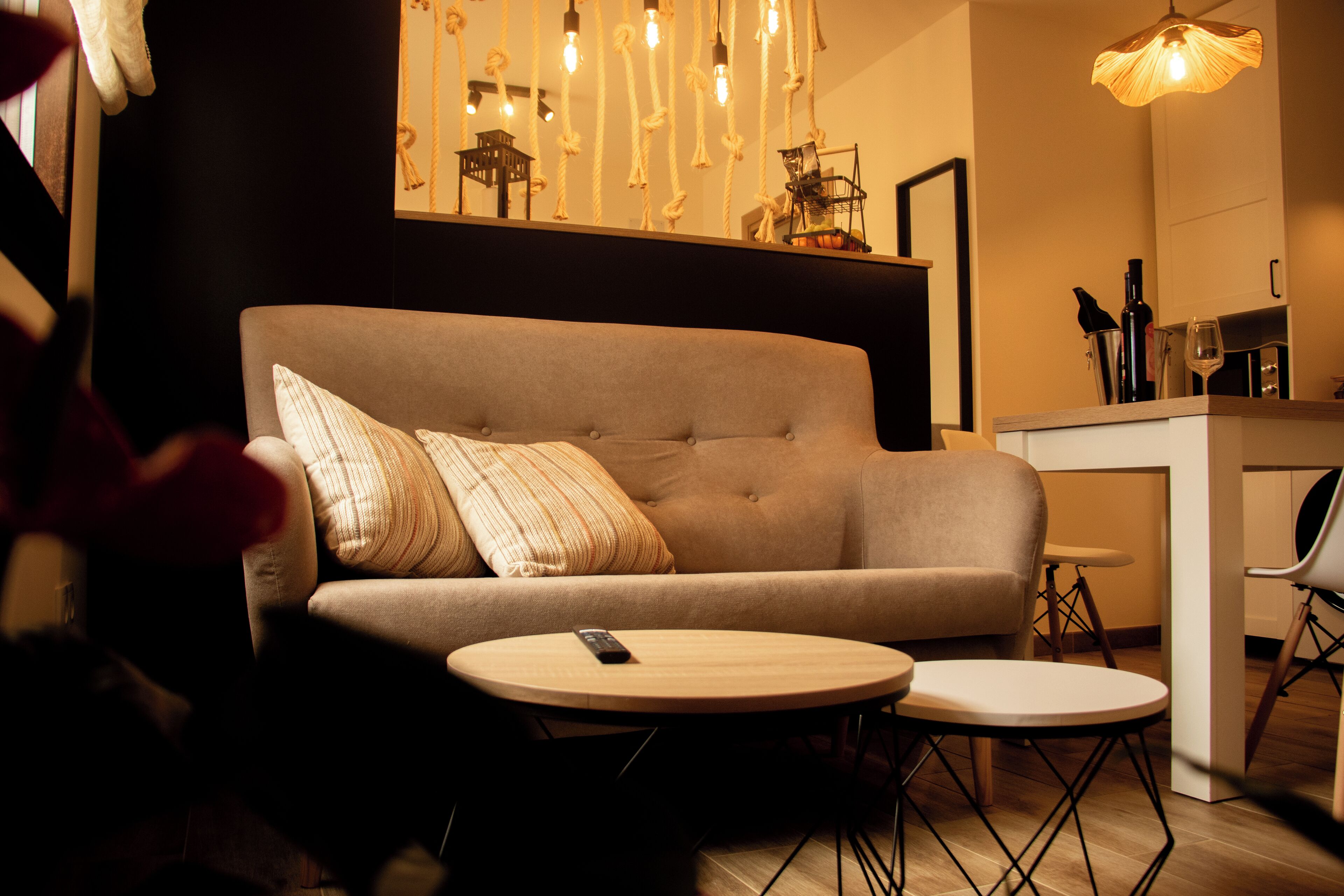 A modern living room with a sofa, two round tables, and a hanging light fixture.