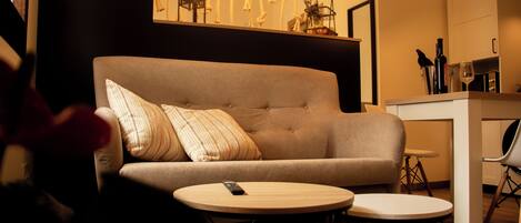 A modern living room with a sofa, two round tables, and a hanging light fixture.