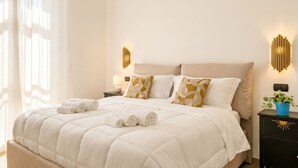 A neatly made bed with pillows, a bedside lamp, and a wall-mounted light fixture.