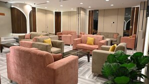 A modern lounge area with multiple sofas and armchairs, a glass coffee table, and large windows. - Durrat Al Jawar (Makkah)