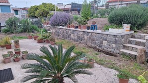 A rooftop garden with various potted plants, a stone wall, and a view of surrounding buildings. - La Campetella. Relaxation within walking distance of downtown. (Ischia)