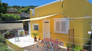 A yellow building with a covered patio, outdoor seating, and potted plants. - La Campetella. Relaxation within walking distance of downtown. (Ischia)