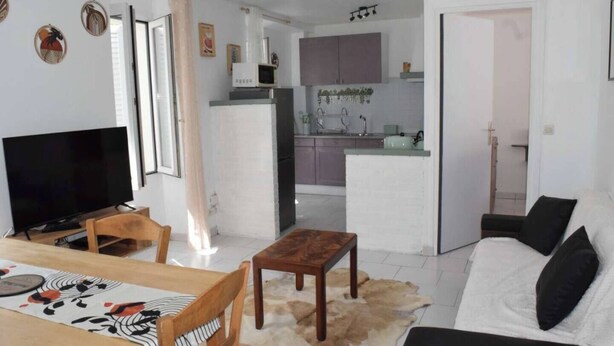 A modern living room with a flat-screen TV, wooden furniture, a sofa, and a dining area with a table. - The Bangor Coon Apartment Liouba (Forges)