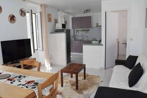 A modern living room with a flat-screen TV, wooden furniture, a sofa, and a dining area with a table. - The Bangor Coon Apartment Liouba (Forges)