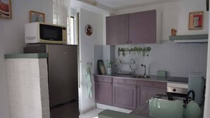 A compact kitchen with a refrigerator, microwave, sink, and kettle. - The Bangor Coon Apartment Liouba (Forges)