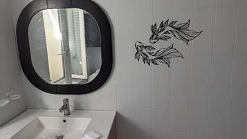 A bathroom with a white sink, a black-framed mirror, and decorative wall art.