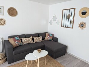 A modern living room with a sectional sofa, a small white table, and decorative wall art.