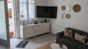 Una sala moderna con un sofá, una mesa de centro, un televisor y un armario blanco.