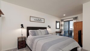 A bedroom with a bed, bedside tables, a wall-mounted lamp, a mirror, and a sliding door to a balcony. - Updated Animas Valley Condo with awesome views (Durango)
