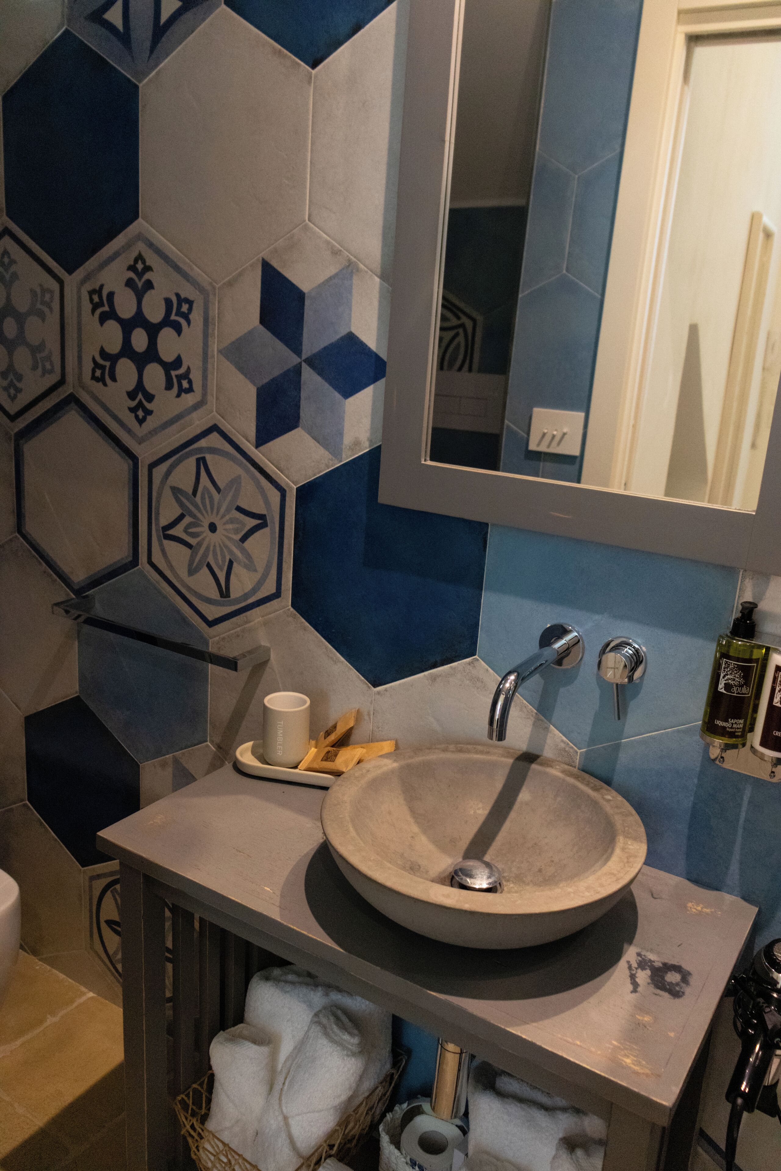 A bathroom with a round sink, a mirror, and a towel rack.
