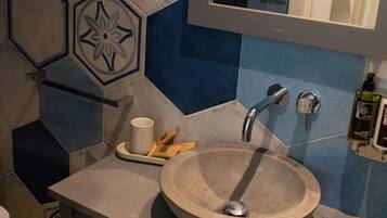A bathroom with a round sink, a mirror, and a towel rack.