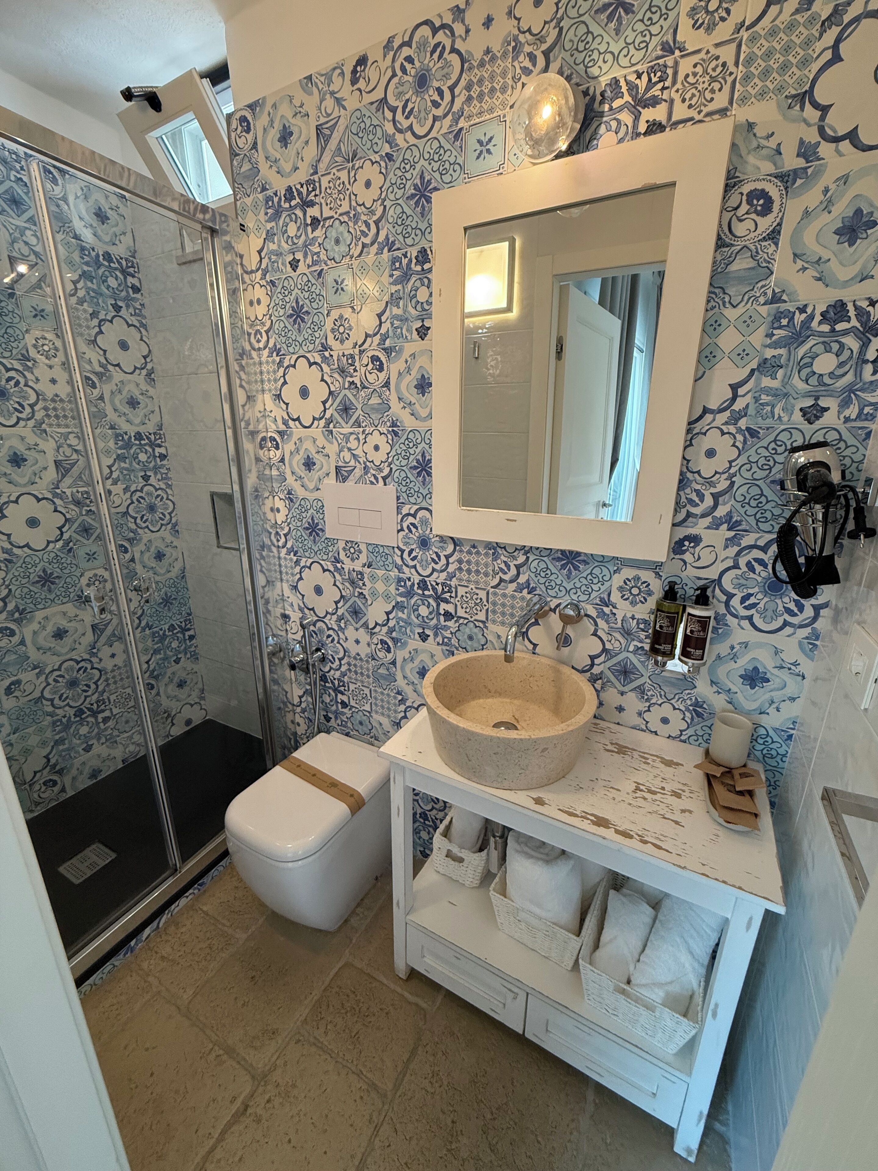 A bathroom with a shower, toilet, sink, and a mirror.