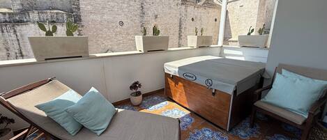 A rooftop terrace with a lounge chair, a small table, and a sofa. There are potted cacti on the terrace.