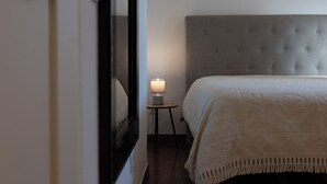 A bedroom with a large bed, a bedside table with a lamp, and a mirror on the wall. - Encanto da Aldeia (Castelo de Vide)
