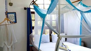 A room with a bed under a blue canopy, a wooden floor, and a white wall with a picture frame. - Villa Noemi by the Sea (Bwejuu)