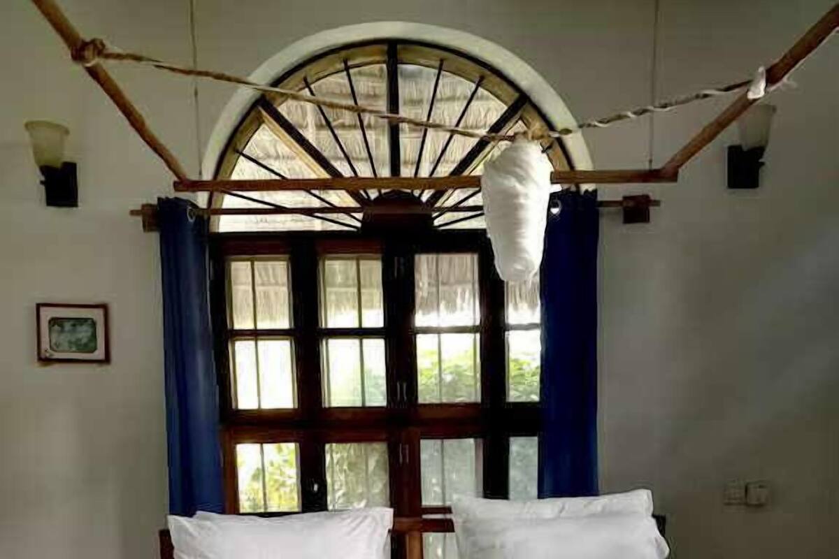 Een hotelkamer met een groot bed, een raam met gordijnen en een decoratieve handdoekopstelling.