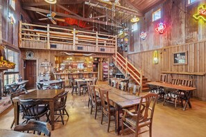 Ein rustikales Interieur mit Holztischen und -stühlen, einer Bar und einer Treppe, die zu einer oberen Ebene führt.