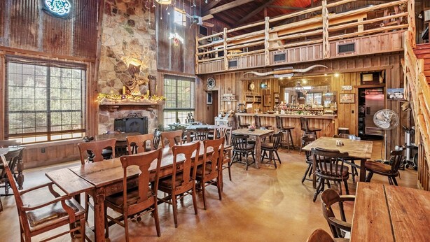 Un interior rústico con muebles de madera, chimenea de piedra y una zona de bar.