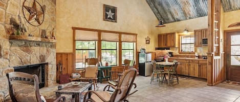 A rustic interior with a stone fireplace, wooden furniture, and a kitchen area.