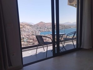 Ein Balkon mit Tisch und Stühlen, der auf eine Stadtlandschaft und ein Gewässer blickt.