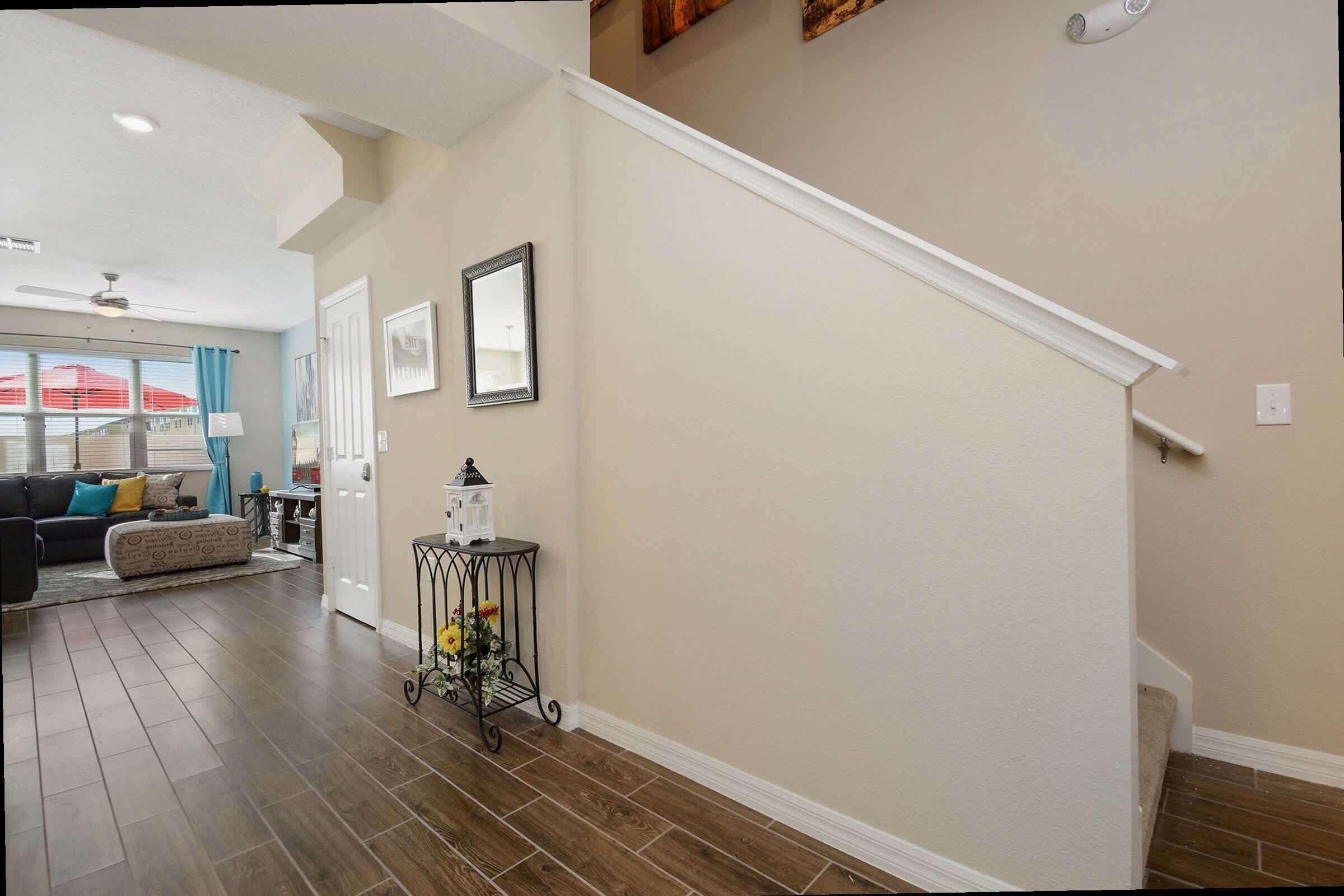 A spacious living room with a dark wood floor, a sofa with cushions, and a dining area with a table and chairs.