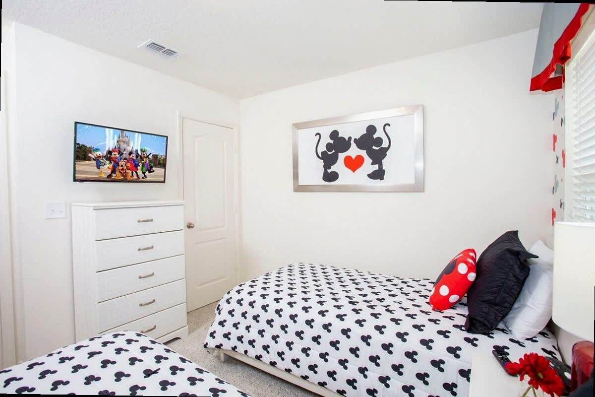 A bedroom with a bed, a dresser, a television, and a wall decoration.
