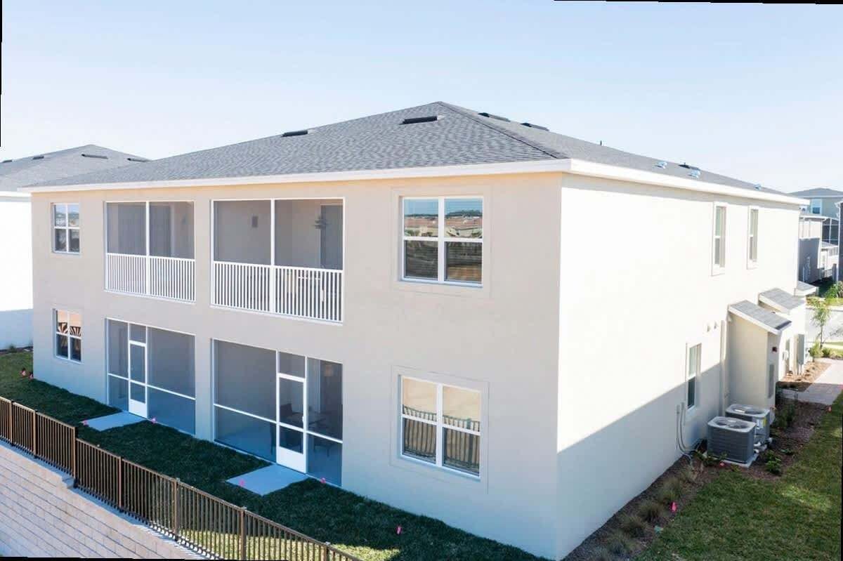 A two-story residential building with a balcony, large windows, and a small attached garage.