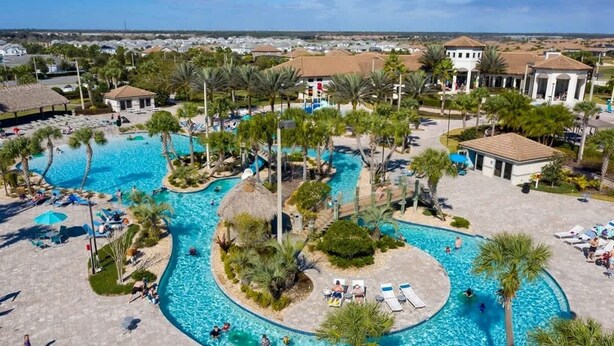 A large outdoor swimming pool with multiple sections, surrounded by palm trees and lounge chairs. - Chic 2Bd Family Retreat With Free Waterpark (Davenport)