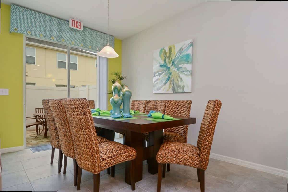 Un coin repas avec une table en bois, des chaises en osier et un tableau accroché au mur.