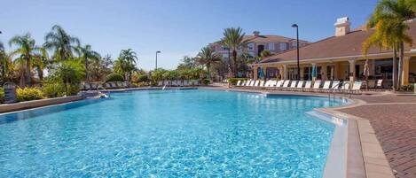 A swimming pool with lounge chairs and palm trees.