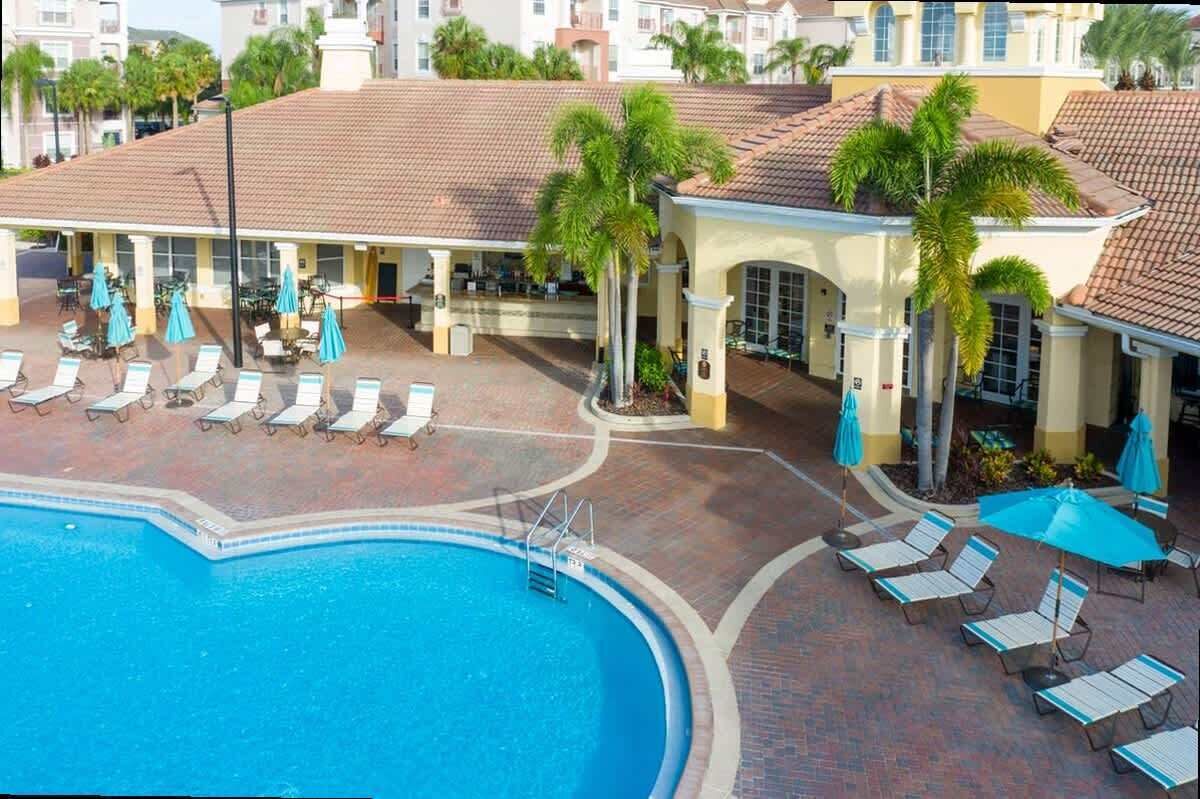 Ein Hotel mit Schwimmbad, Liegestühlen und Palmen.