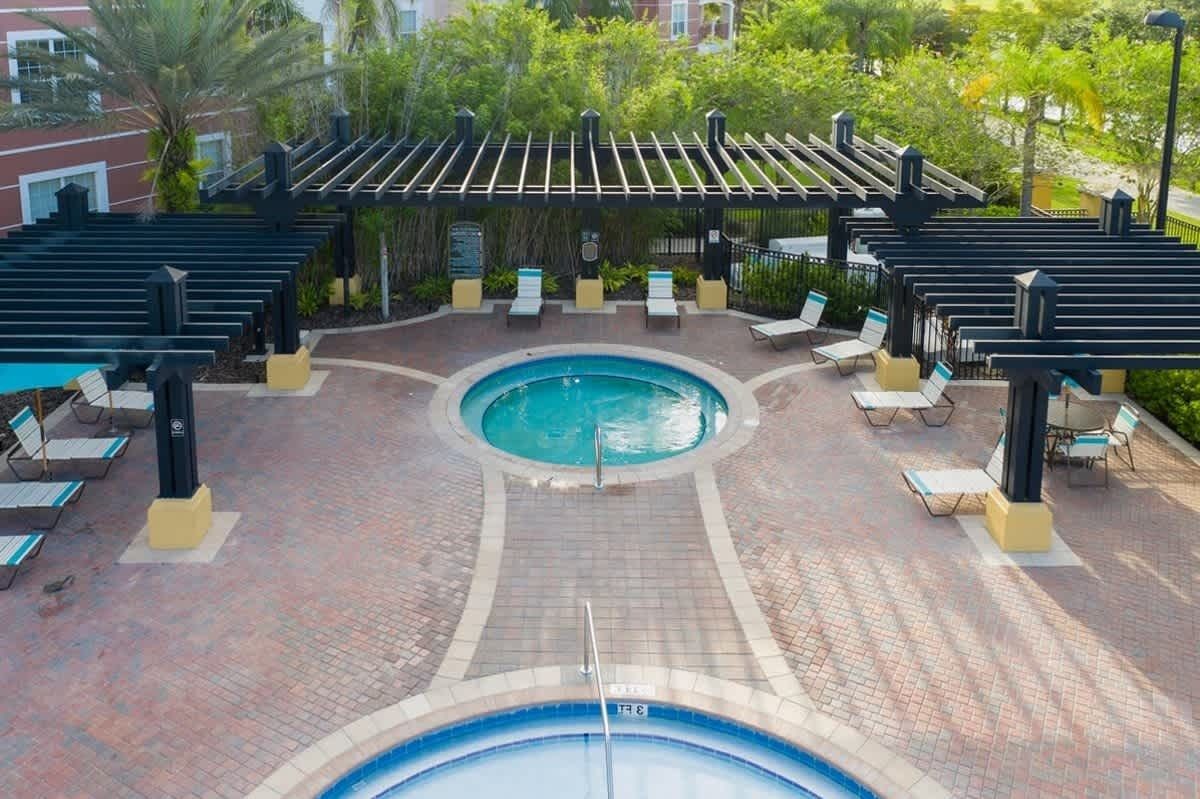 Un área de piscina con piscina circular, sillas de descanso y una estructura de pérgola.