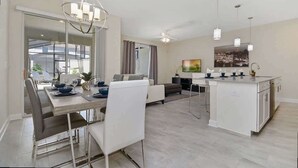 A modern living space with a dining area, kitchen, and seating area. - Bright 4Bd With Pool Resort Perks Near Disney (Kissimmee)