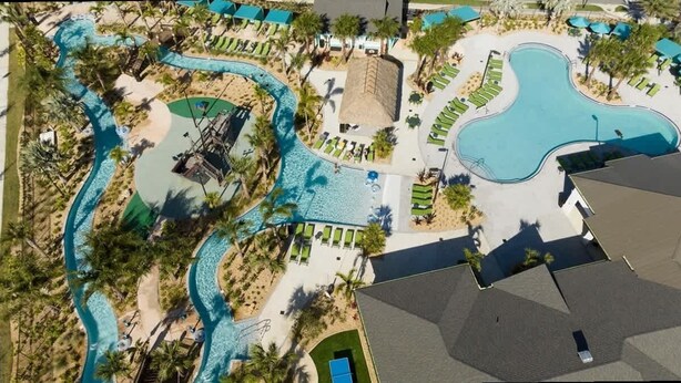 An aerial view of a resort with multiple swimming pools, palm trees, and lounge areas.