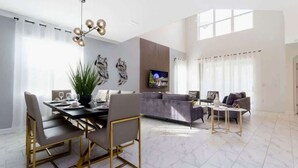 A spacious living area with a dining table, sofas, and a TV.