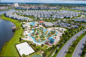 An aerial view of a residential area with a central park featuring a swimming pool, walking paths, and a playground. - Lake View Resort Condo w Lazy River Near Disney (Kissimmee)