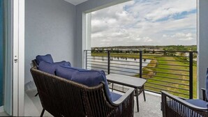 Een balkon met rieten meubilair en uitzicht op een groen landschap.