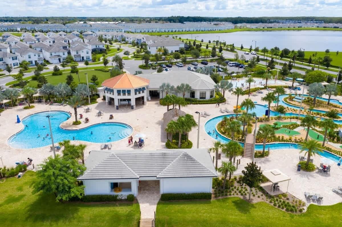 A resort with multiple swimming pools, a central building, and a view of the surrounding area.