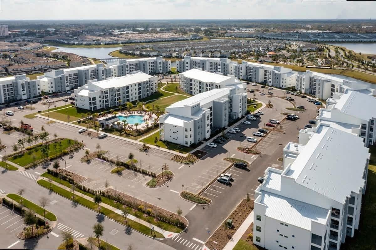 A modern apartment complex with multiple buildings, a central courtyard with a swimming pool, and a parking area.