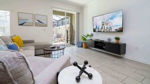 Un salon moderne avec un canapé, une table basse et un téléviseur à écran plat fixé au mur.