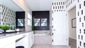 A modern bathroom with a bathtub, a sink, and a toilet. There is a window with a view of the outside. - Family 5BD Spa Pool Game Loft Near Disney (Kissimmee)