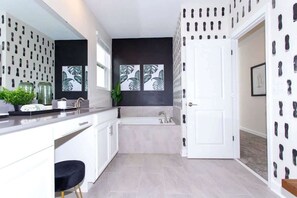 A modern bathroom with a bathtub, a sink, and a toilet. There is a window with a view of the outside. - Family 5BD Spa Pool Game Loft Near Disney (Kissimmee)
