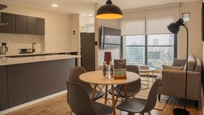 Eine moderne Küche mit Essbereich, einer Couch und einem großen Fenster mit Blick auf die Stadt.