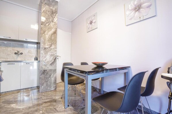 A modern kitchen with marble countertops, a dining table with chairs, and a small island with a bowl.