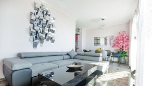 A modern living room with a grey sectional sofa, a black glass coffee table, and a wall art installation. - Kalamata Coastal Charm Modern Seaside Escape (Kalamata)