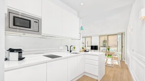 A modern kitchen with white cabinetry, a built-in microwave, and a coffee machine. - Atico Sebastian Souviron - Penthouse in Malaga (Málaga)